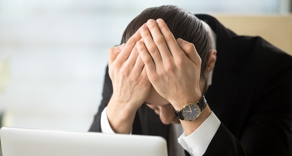 Businessman sitting head in hands shocked because of company bankruptcy, market crash, loss of savings. Young man in despair after receiving dismissal notice, confiscation of property through debt