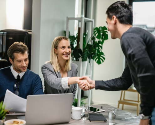 two-financial-advisors-having-meeting-with-young-man-home-female-advisor-is-shaking-hands-with-client-scaled.jpg