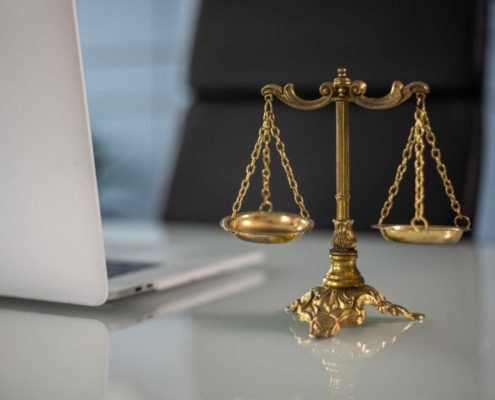 Balança da justiça dourada sobre mesa ao lado de notebook, representando decisão judicial sobre responsabilidade de banco em golpe financeiro