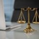Balança da justiça dourada sobre mesa ao lado de notebook, representando decisão judicial sobre responsabilidade de banco em golpe financeiro