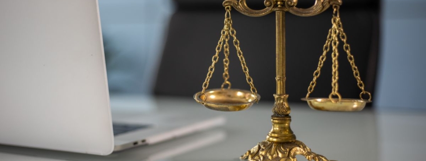 Balança da justiça dourada sobre mesa ao lado de notebook, representando decisão judicial sobre responsabilidade de banco em golpe financeiro