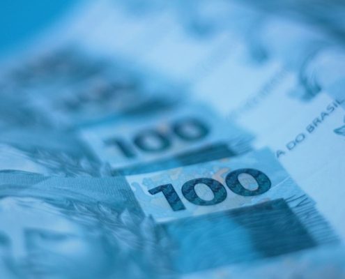 Notas de cem reais dispostas em composição artística, representando prejuízo financeiro de alto valor causado por golpe