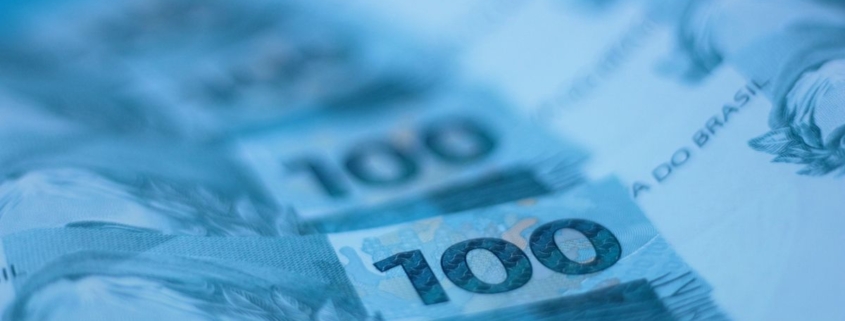 Notas de cem reais dispostas em composição artística, representando prejuízo financeiro de alto valor causado por golpe