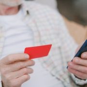Pessoa segurando cartão e celular para pagamento, ilustrando cobrança via Pix Automático