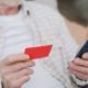 Pessoa segurando cartão e celular para pagamento, ilustrando cobrança via Pix Automático