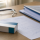 Mesa com receita médica genérica, caixa de medicamento e pasta de documentos para pedido de tratamento fora do rol da ANS